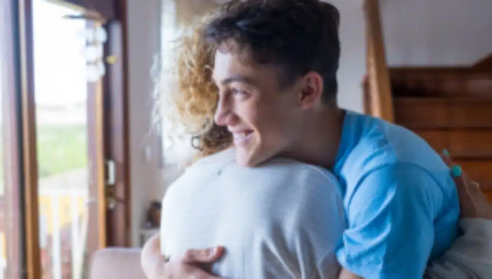 A young man hugs a woman.