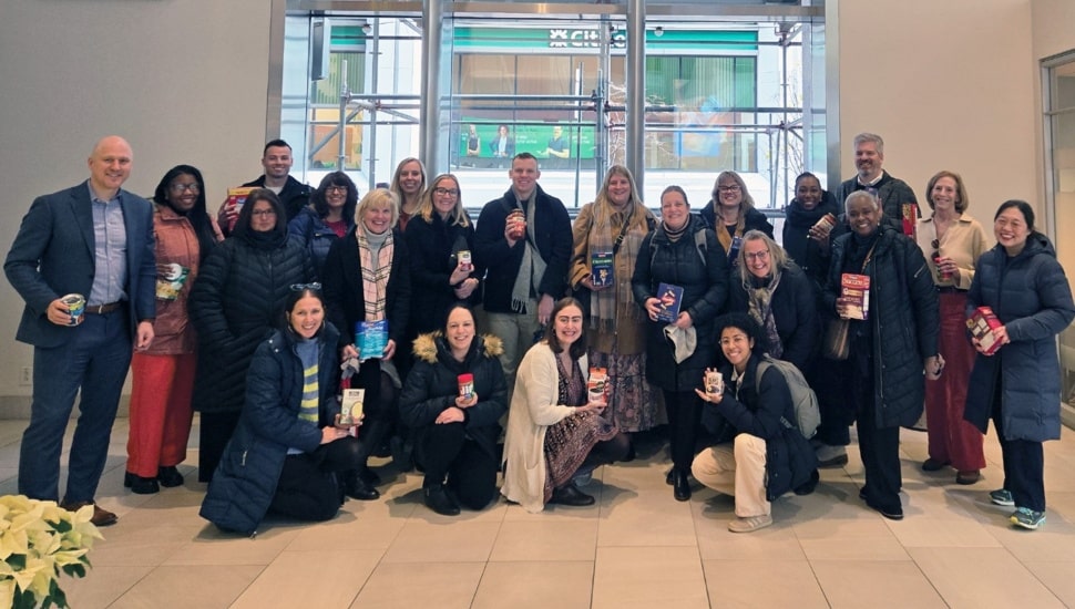 Group photo of a company's employees with food donations.