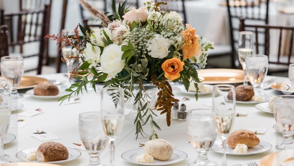 A formal wedding reception table setting with a flower centerpiece.