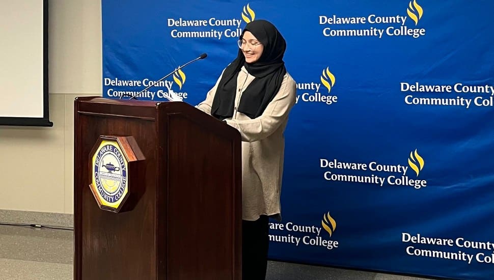 Delaware County Community College student Needah-e-fatema Hafeezali Gangji, pictured behind a podium, was named a 2024 Coca-Cola Leaders of Promise Scholar.