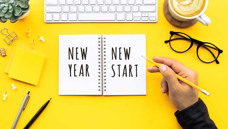 Person writing notebook that says new year and new start.