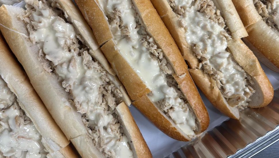 Several cheesesteaks laid out side by side.