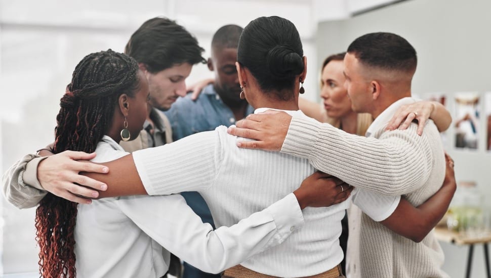 People hug each in a circle for support.