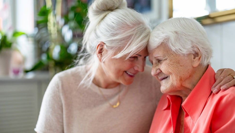 Happy senior woman with her adult daughter at home.