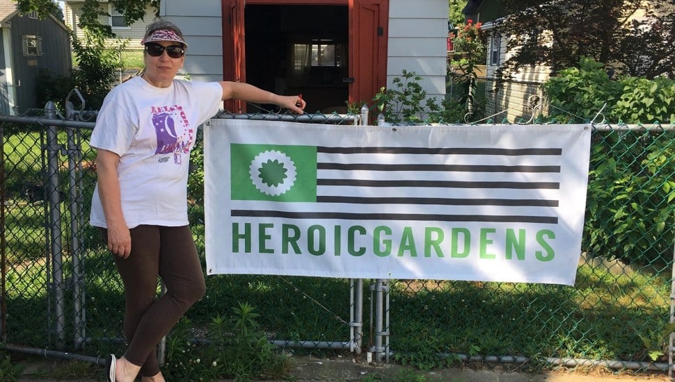Collie Turner stands with the Heroic Gardens sign at the garden in Elkins Park.