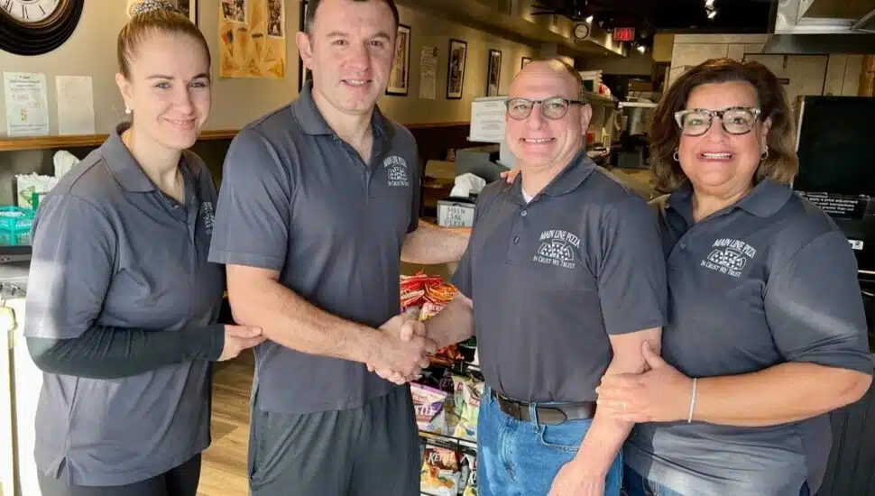 Alban Fezollari (middle-left) and his wife Ana (left) officially acquire Main Line Pizza from founders Robert (middle-right) and Jennifer Saionz (right).