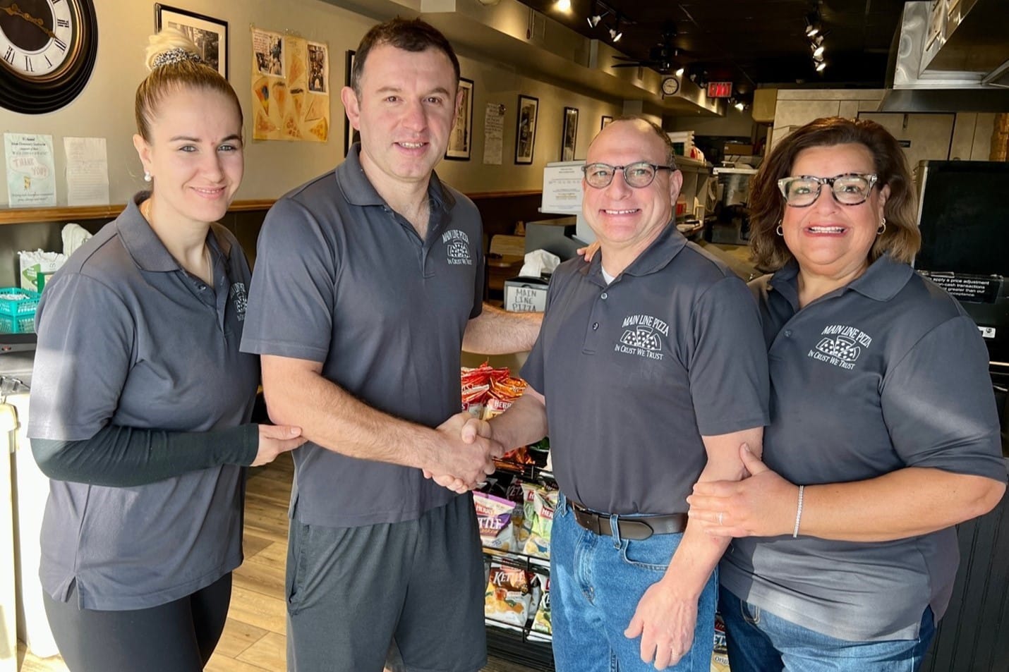 Alban Fezollari (middle-left) and his wife Ana (left) officially acquire Main Line Pizza from founders Robert (middle-right) and Jennifer Saionz (right).