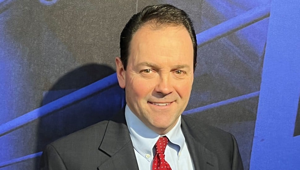 Headshot of business executive in dark suit and red tie.