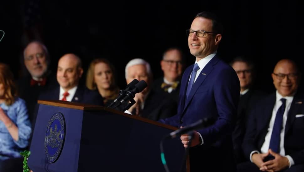 Pennsylvania Gov. Josh Shapiro speaking at a podium with several officials standing behind him.