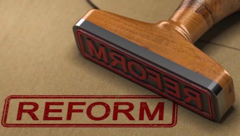 3D illustration of a rubber stamp with the word reform stamped on kraft paper envelope.