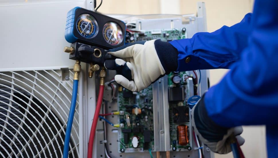 Close up of maintenance worker/technician checking refrigerant liquid and condensor unit.