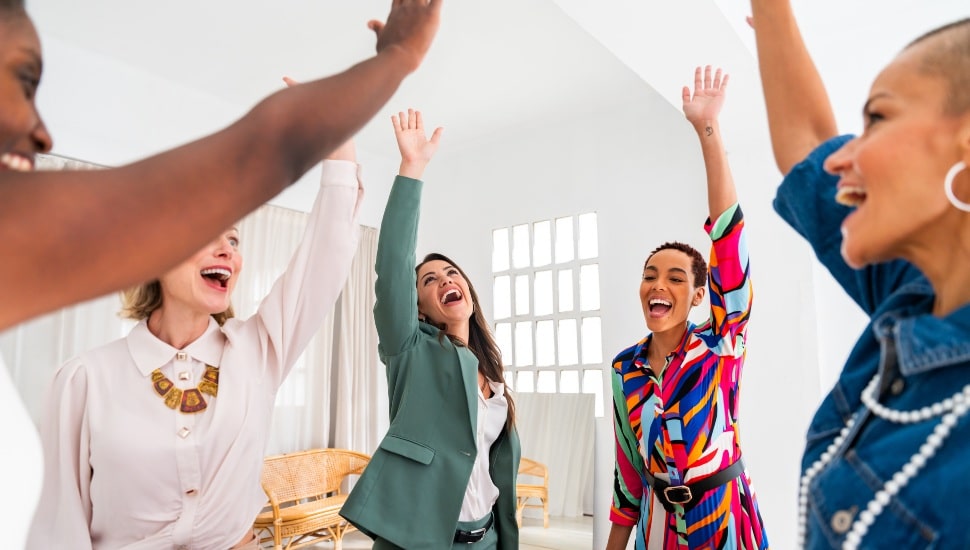 Women entrepreneurs give a high five in celebration of their success.