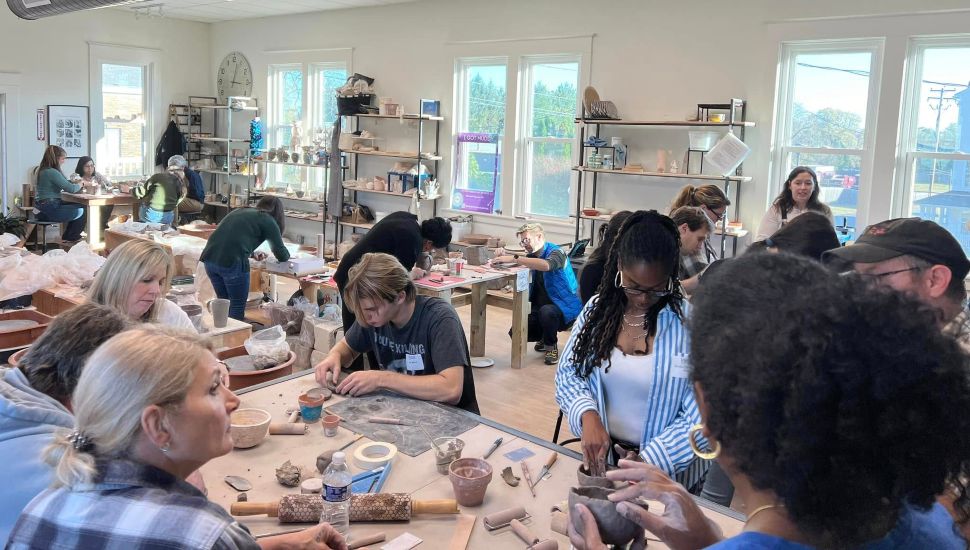 People are working with clay sculptures at a table.