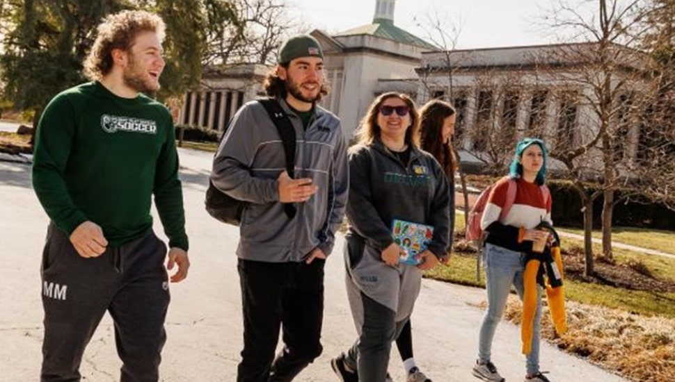 College students walk leisurely on campus.