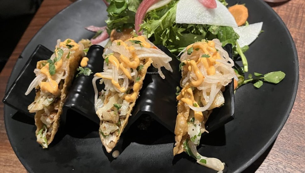 Three vegetarian tacos on a plate.
