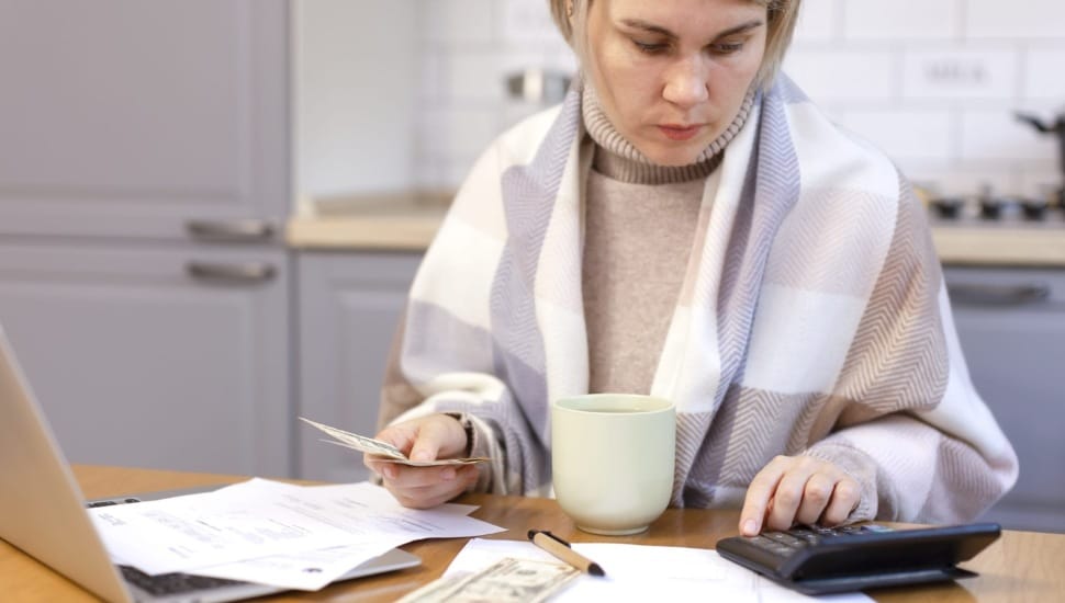 Woman pays bills at her kitchen table.
