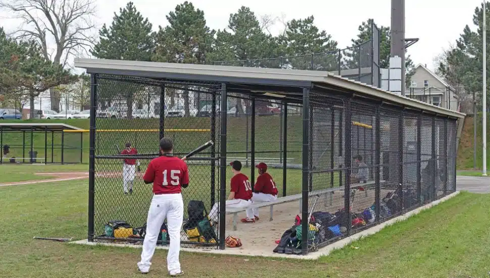 A small shelter from Poligon provides cover for a dugout at a little league game.