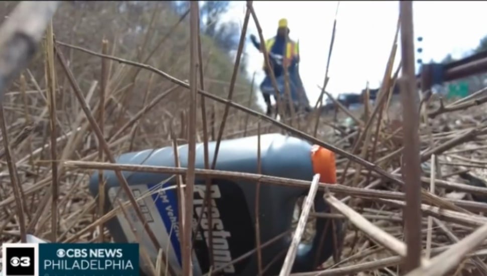 A tossed bottle in the brush along the side of the Blue Route with a PennDOT crew member seen above.
