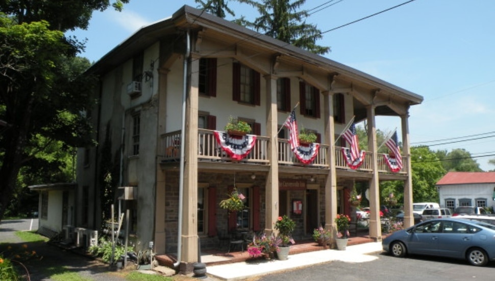 The front of a historic building with windows, balconies and pillars, the Carversville Inn adorned with patriotic bunting in Carversville.