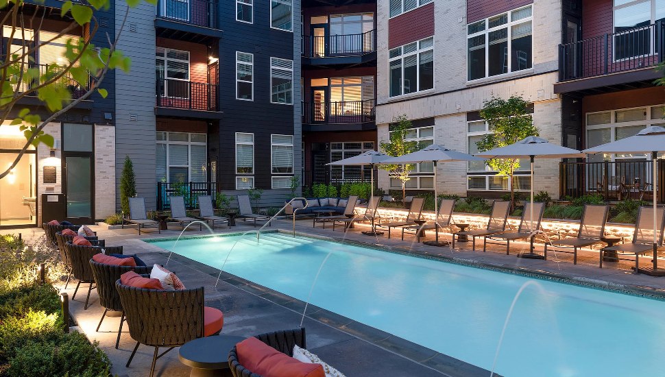 A group of apartments with a swimming pool at night.