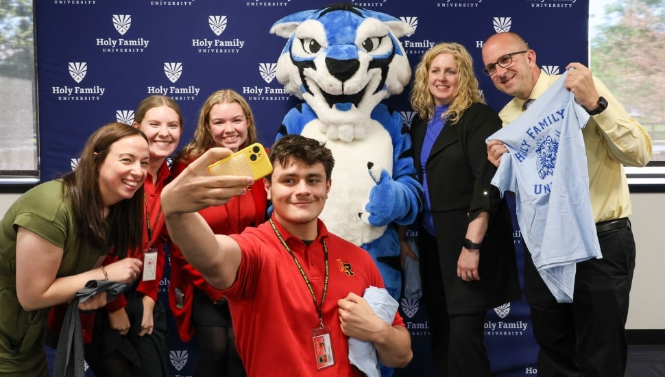 Students and administrators pose for a selfie with mascot.