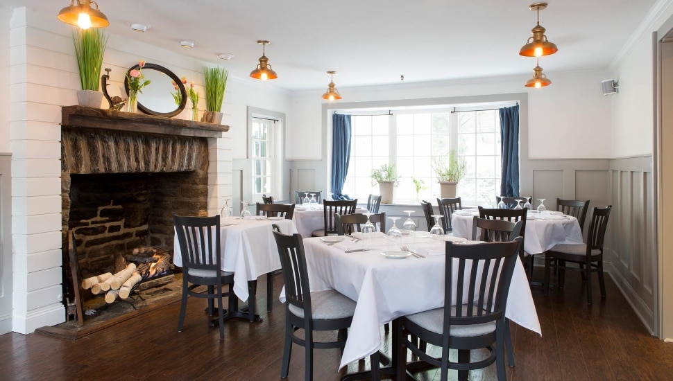 An elegantly-set table and chairs near a fireplace at the Jansen Restaurant in Mount Airy.