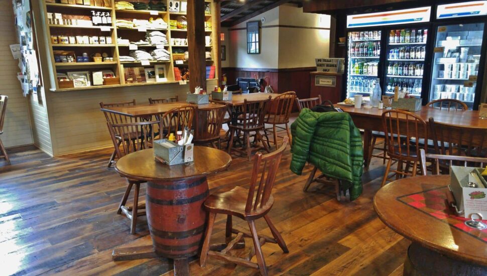 An inside look at Lumberville General Store with wooden floors, barrel tables and chairs and an old-fashioned counter.