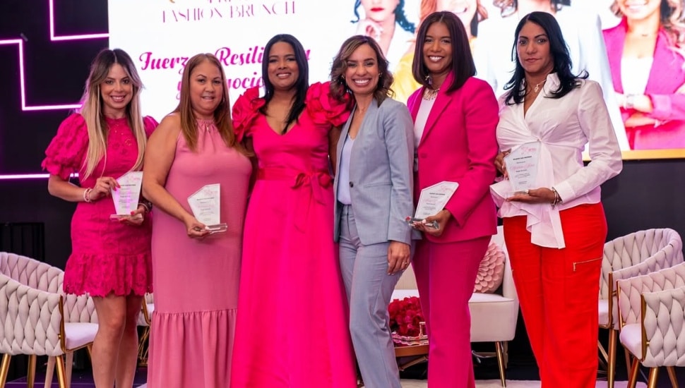 Six Latina women entrepreneurs wearing pink, red and orange dresses and slacks, with one in a off-blue suit.