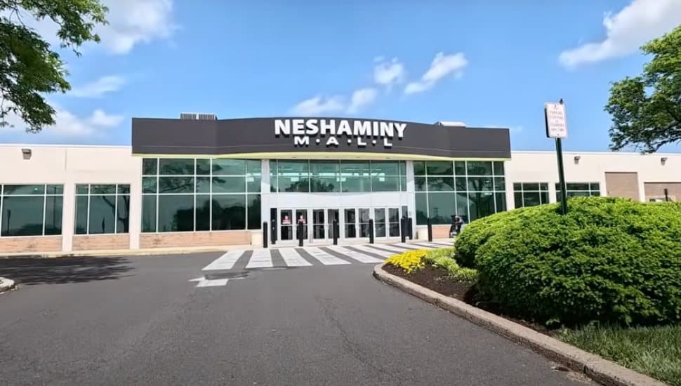 The outside entrance to the Neshaminy Mall with shrubs and a paved lot.