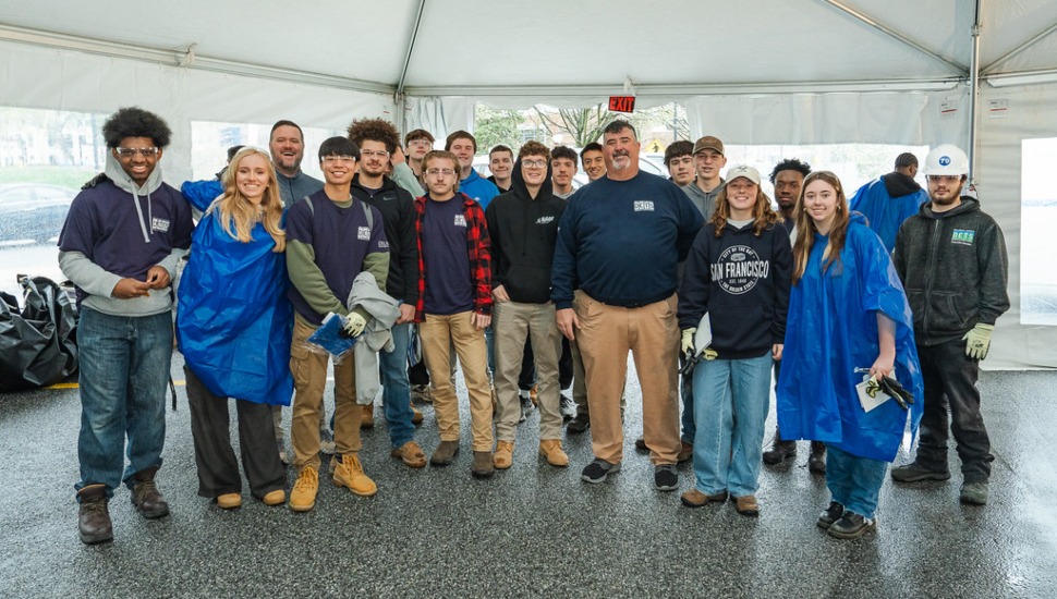 High school students pose for a group photo inside a tent.