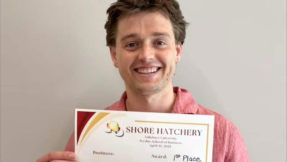 Headshot of Jake Henry holding his 1st place award for k. He is smiling, has brown hair and a red collared shirt.