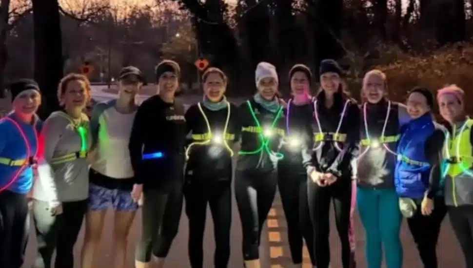 JoAnn Meyer with other members of her running group "Run Strong" in a nighttime outdoor group photo.