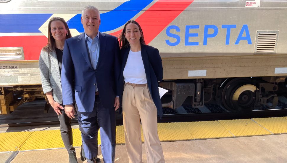 From right, Trish McFarland, Bernard Dagenais, and Laura Manion stand on platform with SEPTA train behind them.