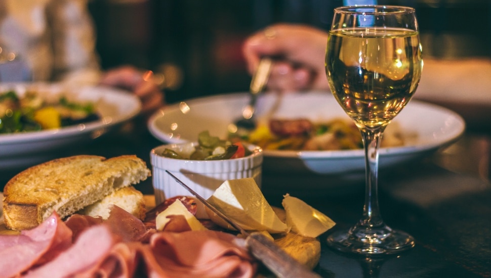 An elegant table with a glass of wine, a main dish Italian entree, and a bowl of soup.