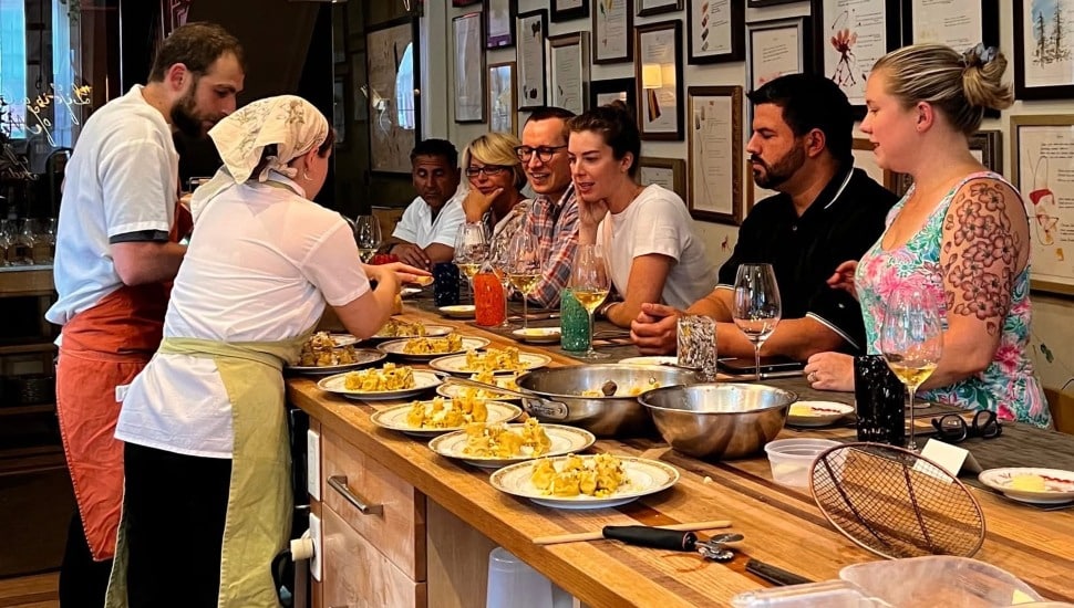 People standing at a table sampling different foods.
