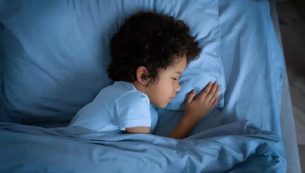 Young boy laying in his bed, sleeping on his side.