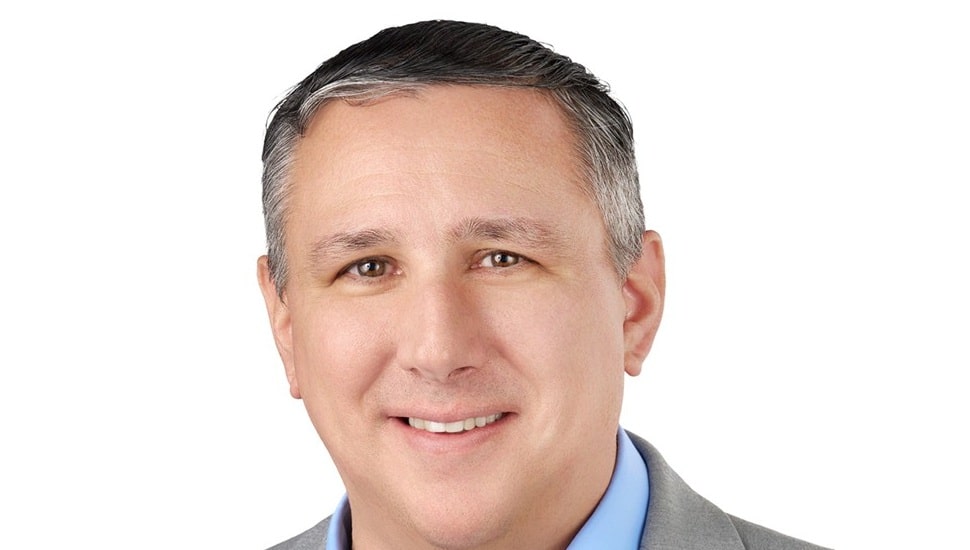Headshot of middle-aged white male bank executive in gray suit and blue collared shirt.