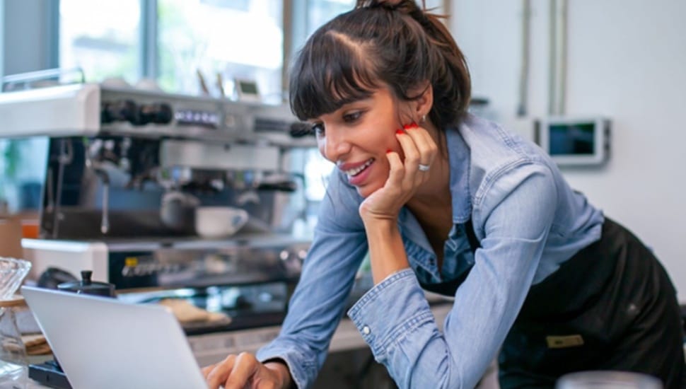 Female small business owner looks at finances on her laptop.