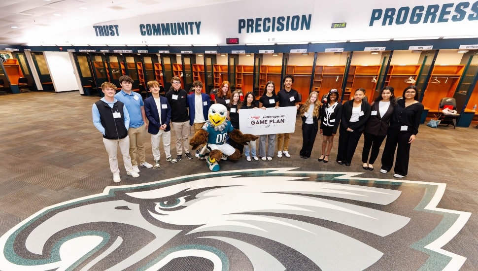 Group photo of student entrepreneurs in pro football locker room.