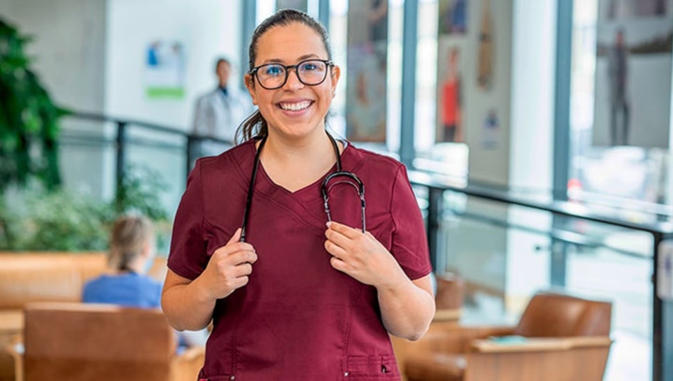 Female nursing student in red scrubs and glasses.