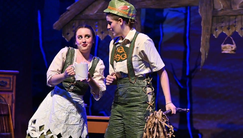 Two cast members of "Hansel & Gretel" on stage at WCU. They are dressed in green and white traditional German attire and are rehearsing on stage.