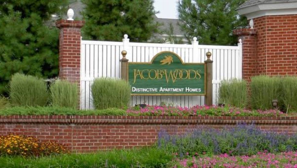 A wooden sign, wooden fencing and landscaping announcing Jacob's Woods.