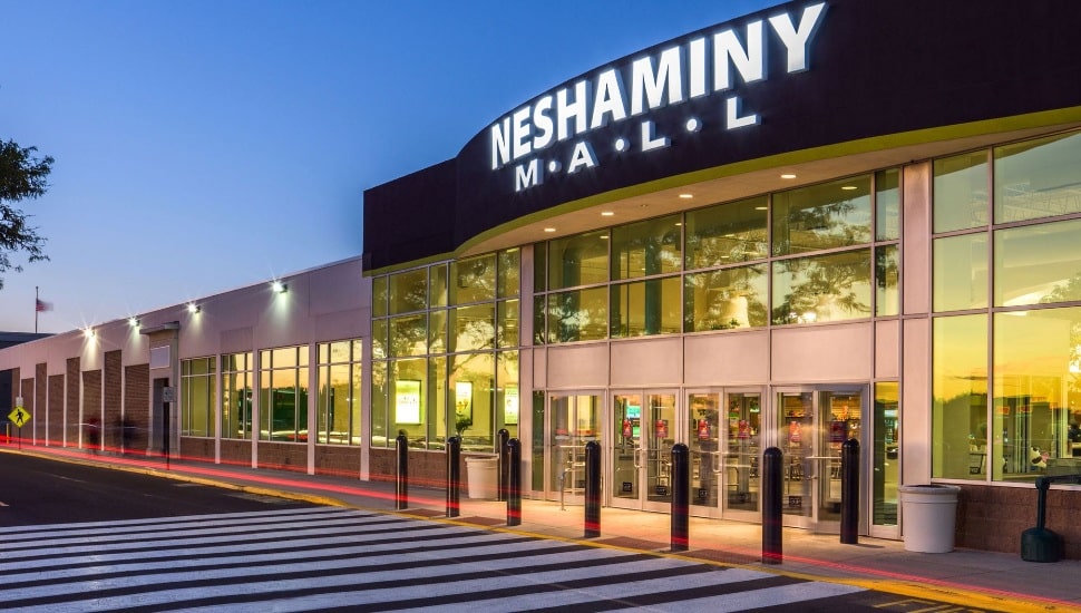 A nighttime view of the front entrance to Neshaminy Mall, with a lit mall sign and other lights.