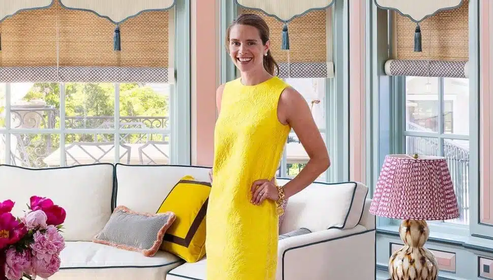Lucy O'Brien in a yellow dress standing amidst one of her redesigned rooms.