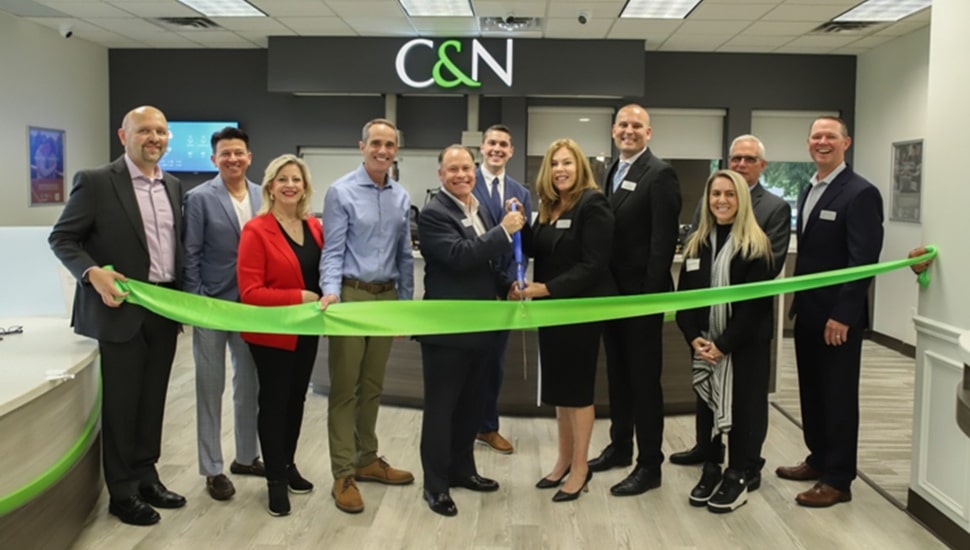 Bank executives cut ribbon on new office location.