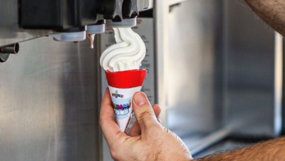 Ice cream from a dispenser going into a gummi cone.