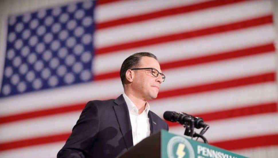 Josh Shapiro stands in front of a giant American Flag.
