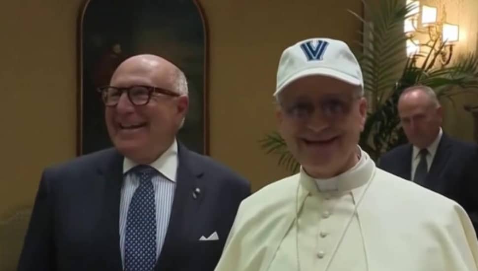 Pope Leo XIV wears a Villanova hat that he received as a gift from the National Italian American Foundation. He is standing with a man who is unidentified.
