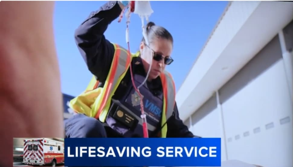 A paramedic monitors a blood transfusion during a training session.