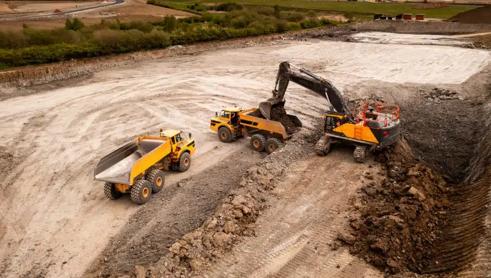 Aerial view of a crane and truck moving earth and soil on a brownfield site.